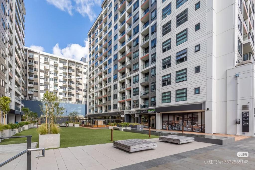 a large apartment building with two benches in a courtyard at Luxury and Morden Deux & Furry Friends welcome in Auckland