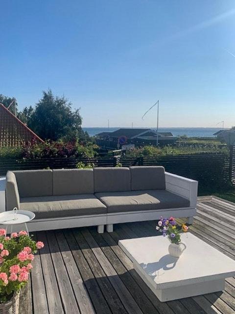 a couch sitting on top of a deck with flowers at Functionalist House Only 100 Steps To The Beach in Haderslev