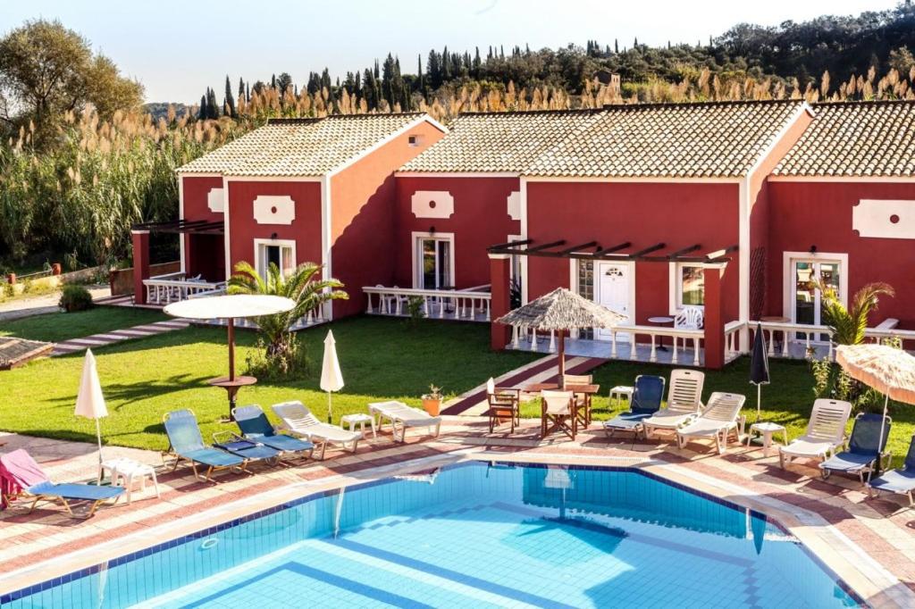 a villa with a swimming pool in front of a house at Haroula Apartments in Sidari
