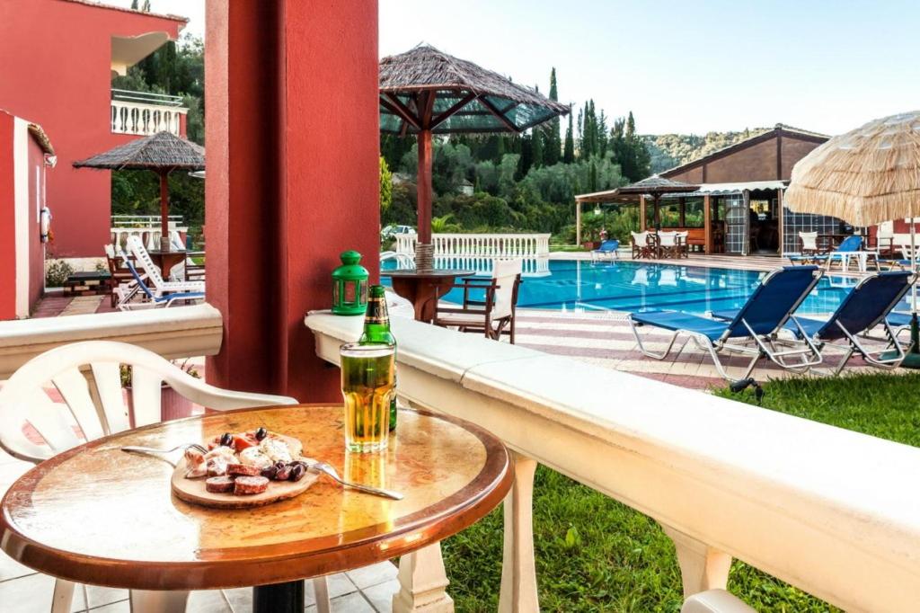 a table with a bottle of beer and a plate of food at Haroula Apartments in Sidari