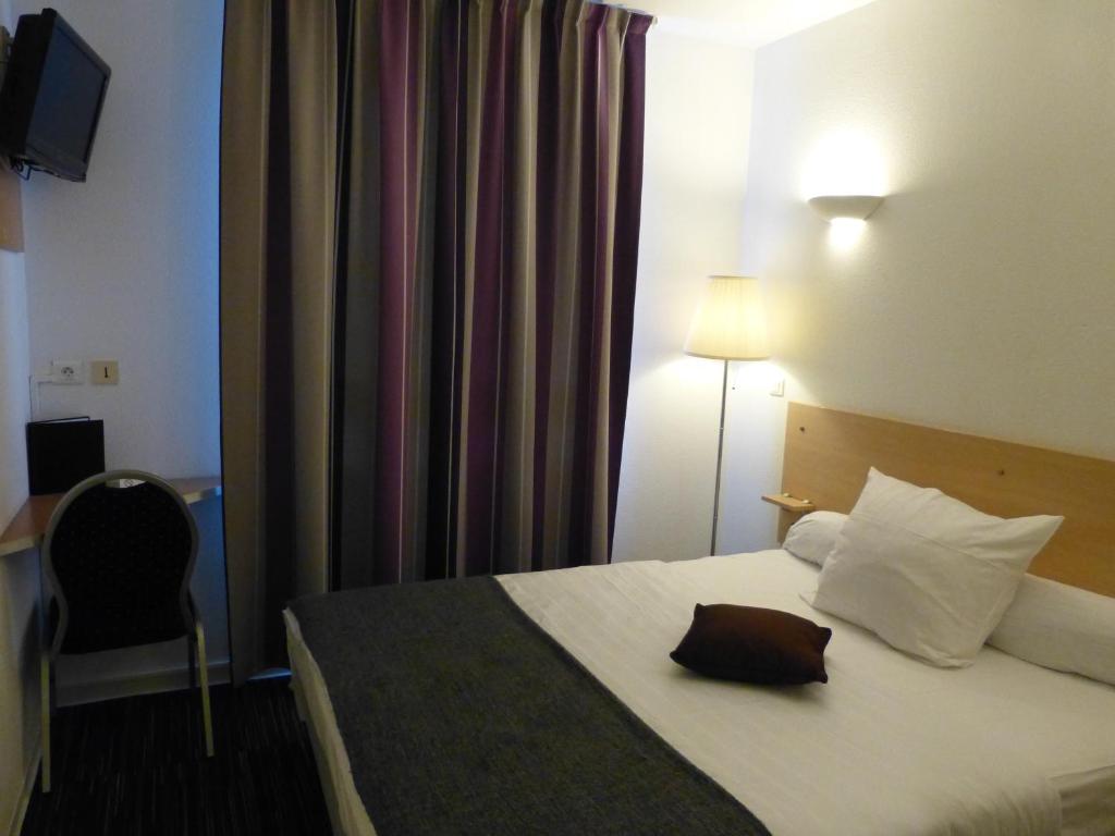 a hotel room with a bed and a chair at Hotel Premium in Forbach