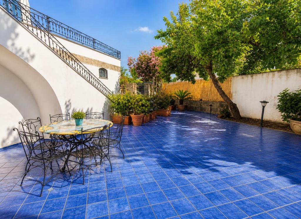 a patio with a table and chairs on a blue tile floor at Domus Pannella - Endless Summer in Lacco Ameno