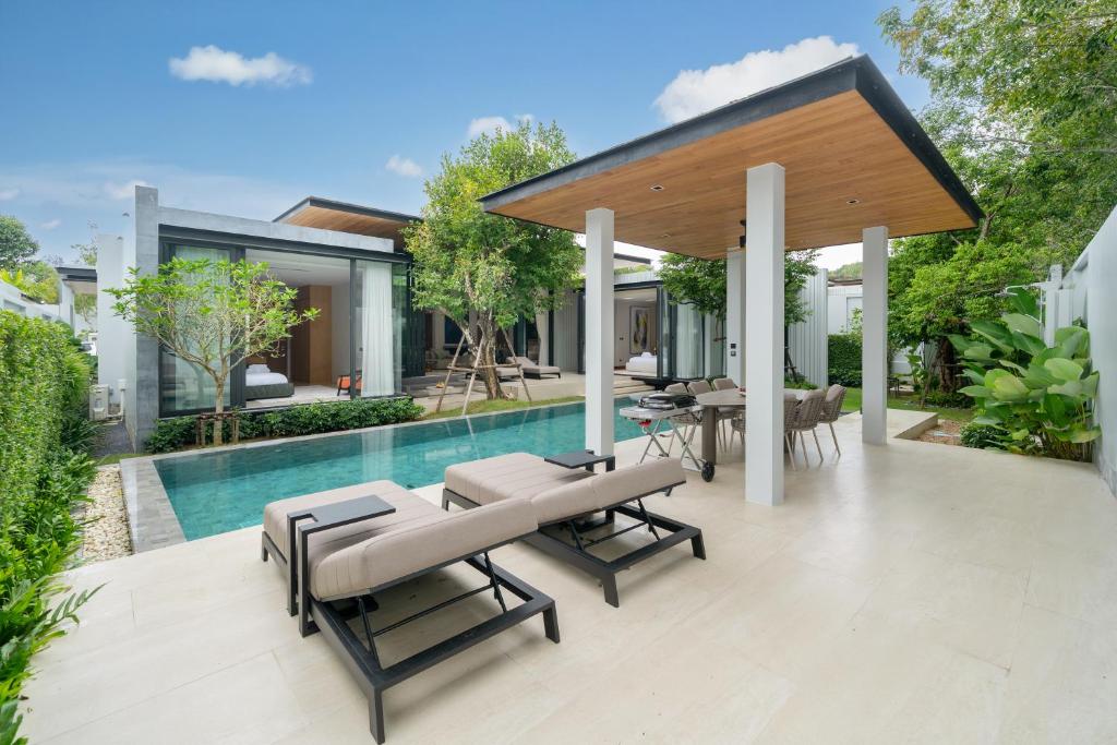an outdoor patio with tables and chairs and a swimming pool at Botanica Foresta 4BDR by Villacarte in Ban Phru Champa