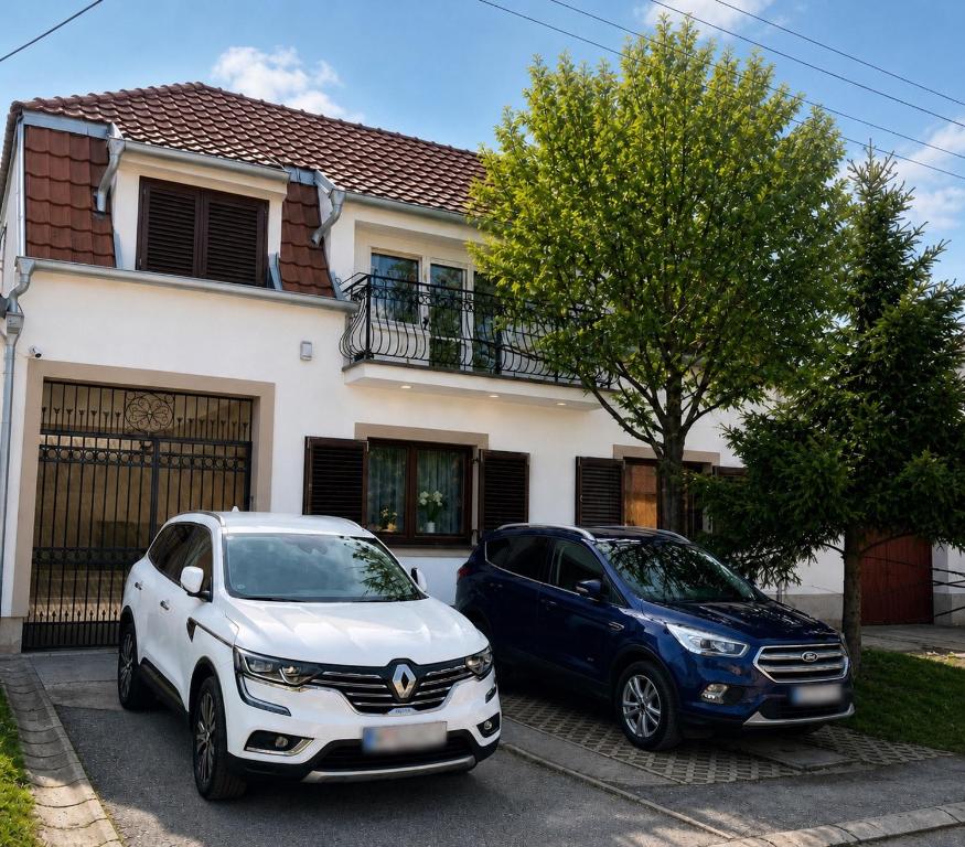 two cars parked in front of a house at La Perla Apartman 1 in Bela Crkva