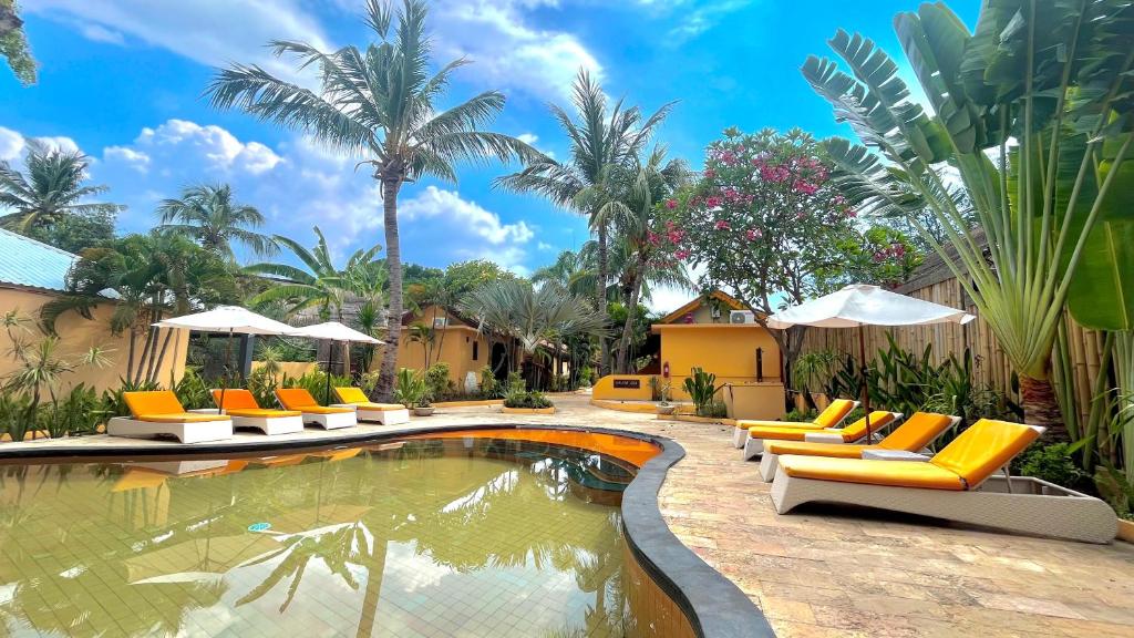 a pool at a resort with lounge chairs and umbrellas at Laguna Gili in Gili Trawangan