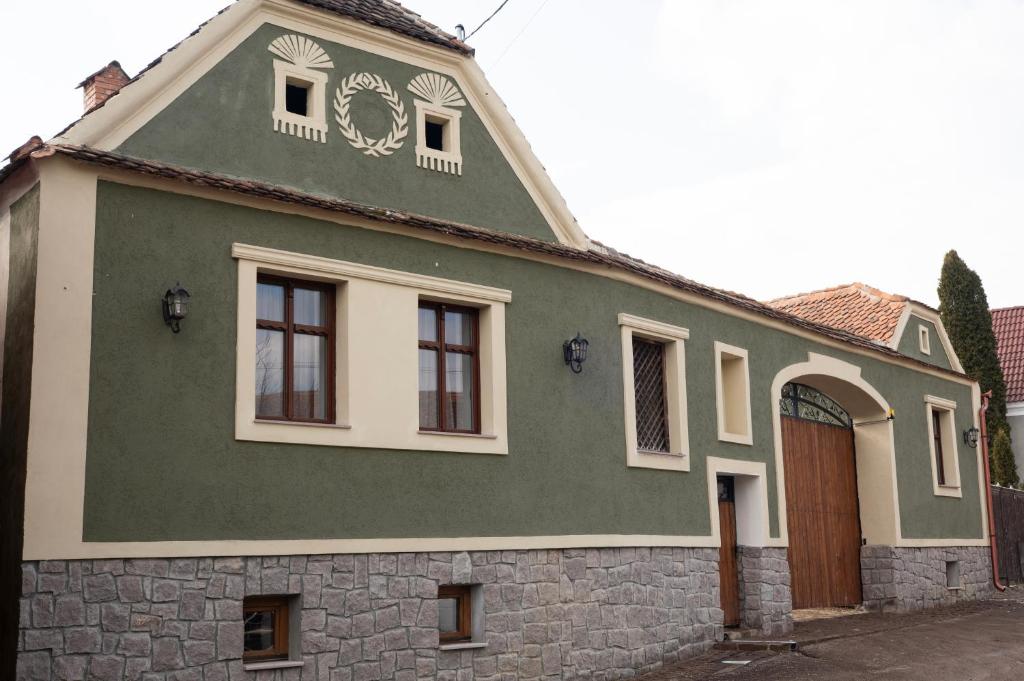 a green and white house with a stone wall at Rácz Vadászkúria in Racoşu de Sus