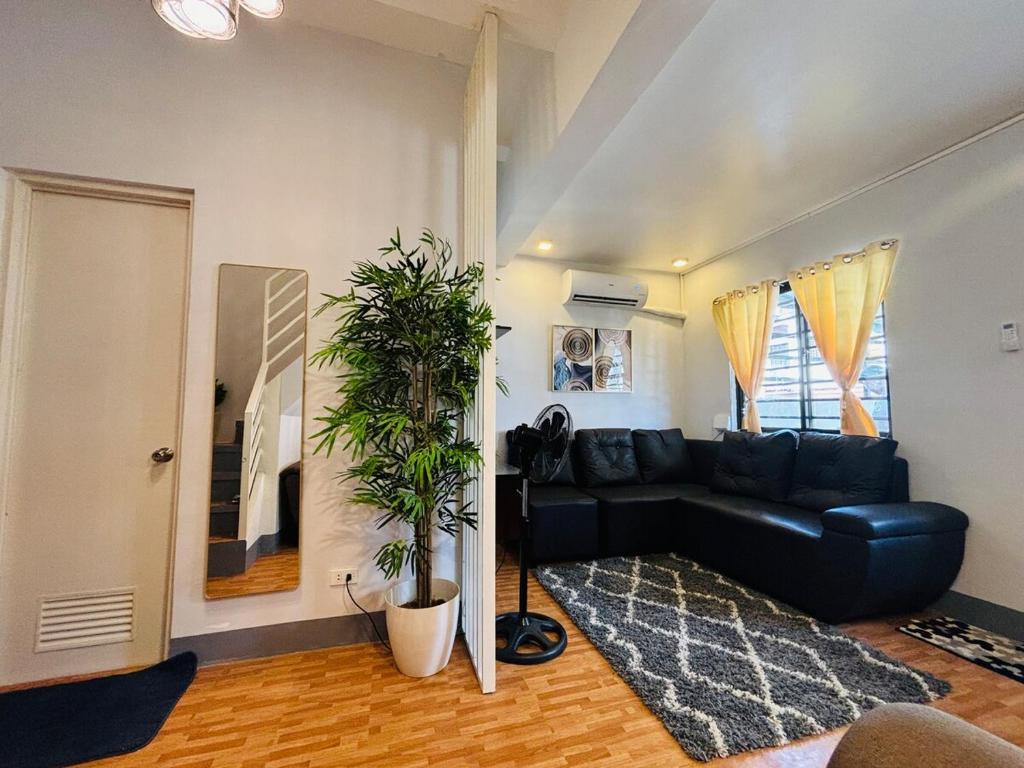 a living room with a black leather couch and a plant at Breena & Dhanie's Haven I in Labac
