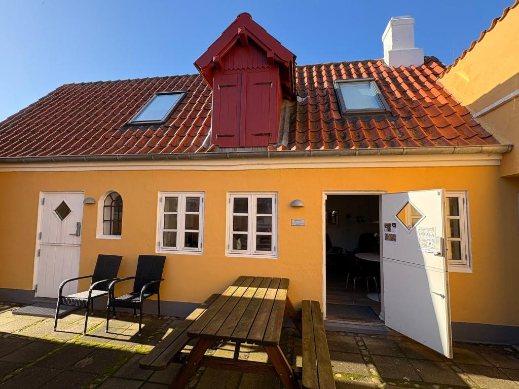 a small yellow house with a table and chairs at Pakhuset, DownTownSkagen in Skagen