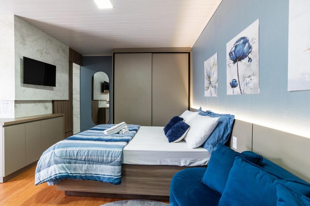 a bedroom with a large bed and a couch at Studio c Piscina, AC e Café Novo Hamburgo in Novo Hamburgo