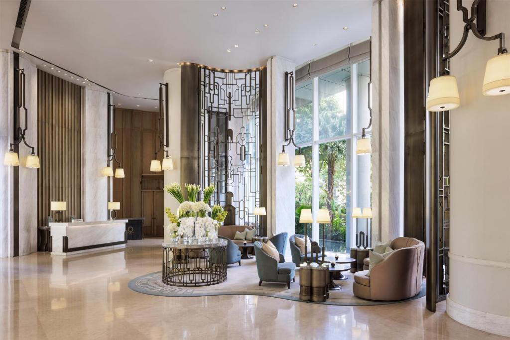 A polished lobby with lounge seating, floral arrangements, marble surfaces and garden-facing windows.