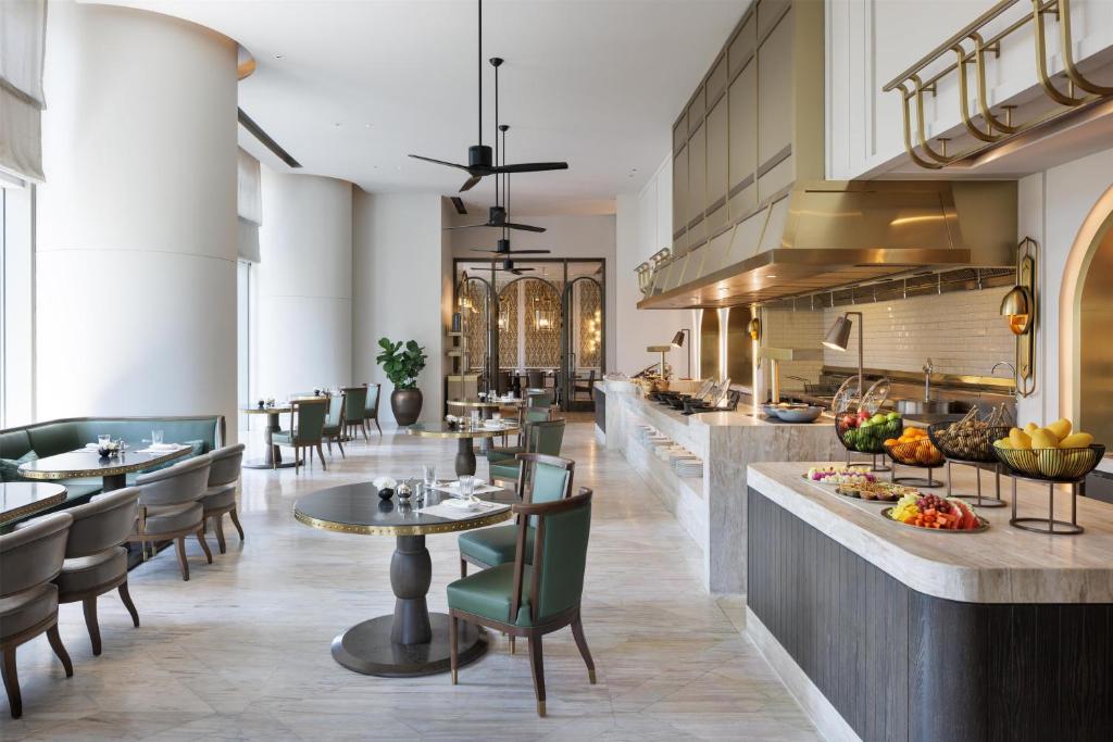 A bright buffet-style dining room with an open kitchen and city-facing tables.