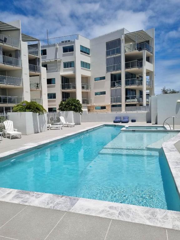 a swimming pool in front of some apartment buildings at Oceanfront Ground Floor Apartment - Dwell 3 in Bargara in Bargara