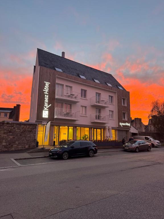 a building with cars parked in a parking lot at Karaez Hôtel - BritHotel Carhaix in Carhaix-Plouguer