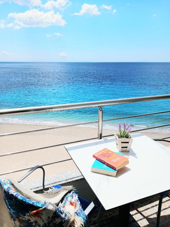 a table and a book on a balcony overlooking the ocean at NaDim rooms in Himare