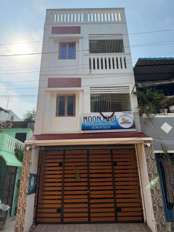 a tall white building with a large garage door at Moon Hug Boutique Beach House in Auroville