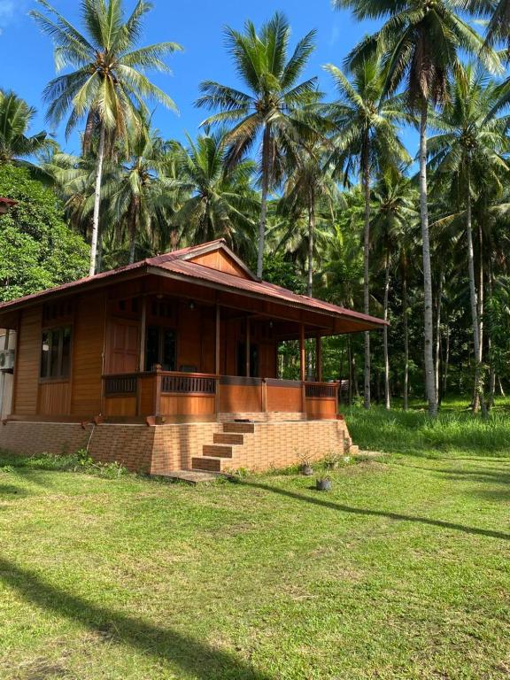 a house with palm trees in the background at Ghia Boutique Homestay in Batuangus