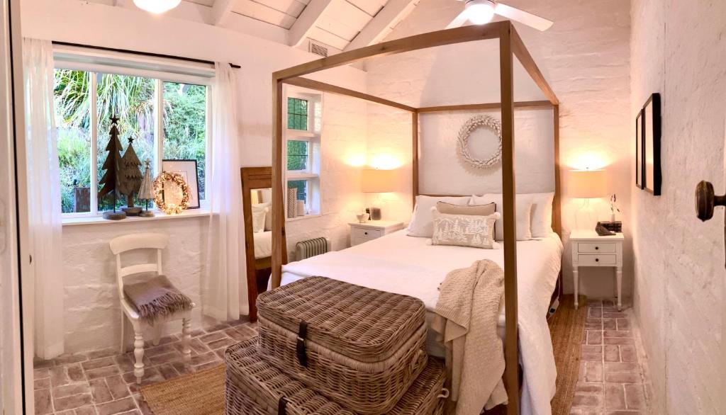 a bedroom with a canopy bed and a window at ONE WEE COTTAGE Bring your dog and enjoy a cosy romantic winter fireside stay in Healesville