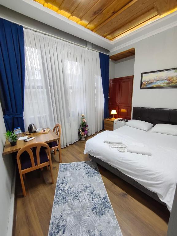ein Schlafzimmer mit einem großen Bett, einem Tisch und einem Schreibtisch in der Unterkunft Kule Pansiyon in Bursa