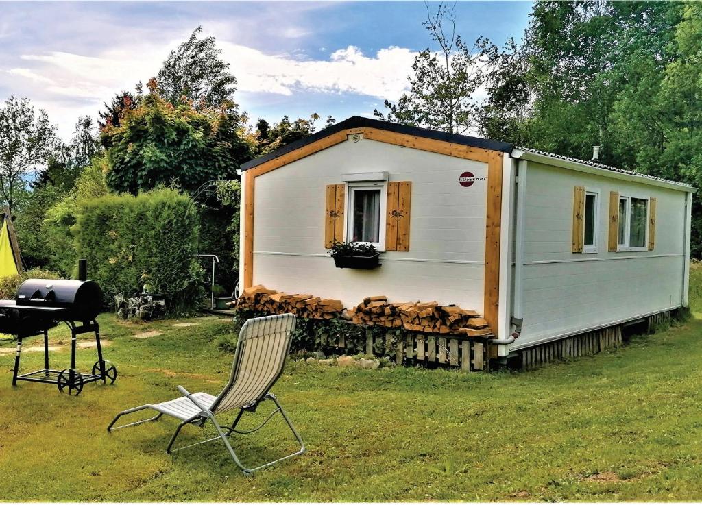 a tiny house with a grill and a chair at Holiday home Rozika in Slovenj Gradec