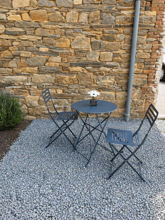 a table and two chairs in front of a brick wall at Chez Mimi in Maubert-Fontaine