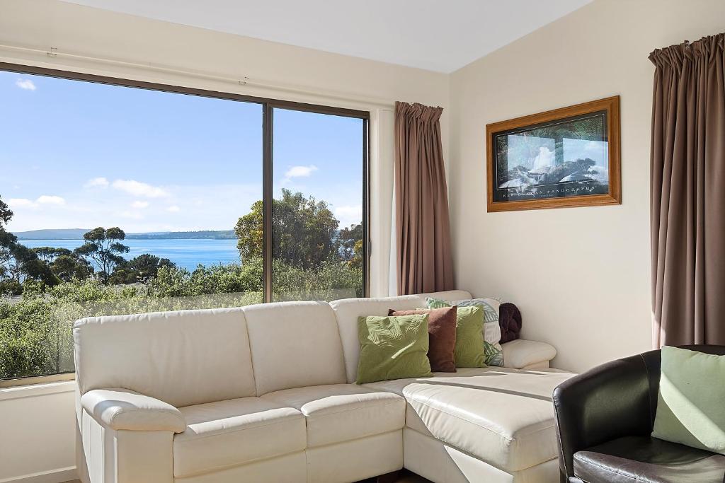 uma sala de estar com um sofá branco e uma grande janela em Mirramar House em Kingston Beach
