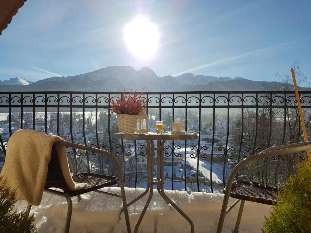 a table and chairs on a balcony with a view at Pokoje Widokowe Szymaszkowa in Zakopane