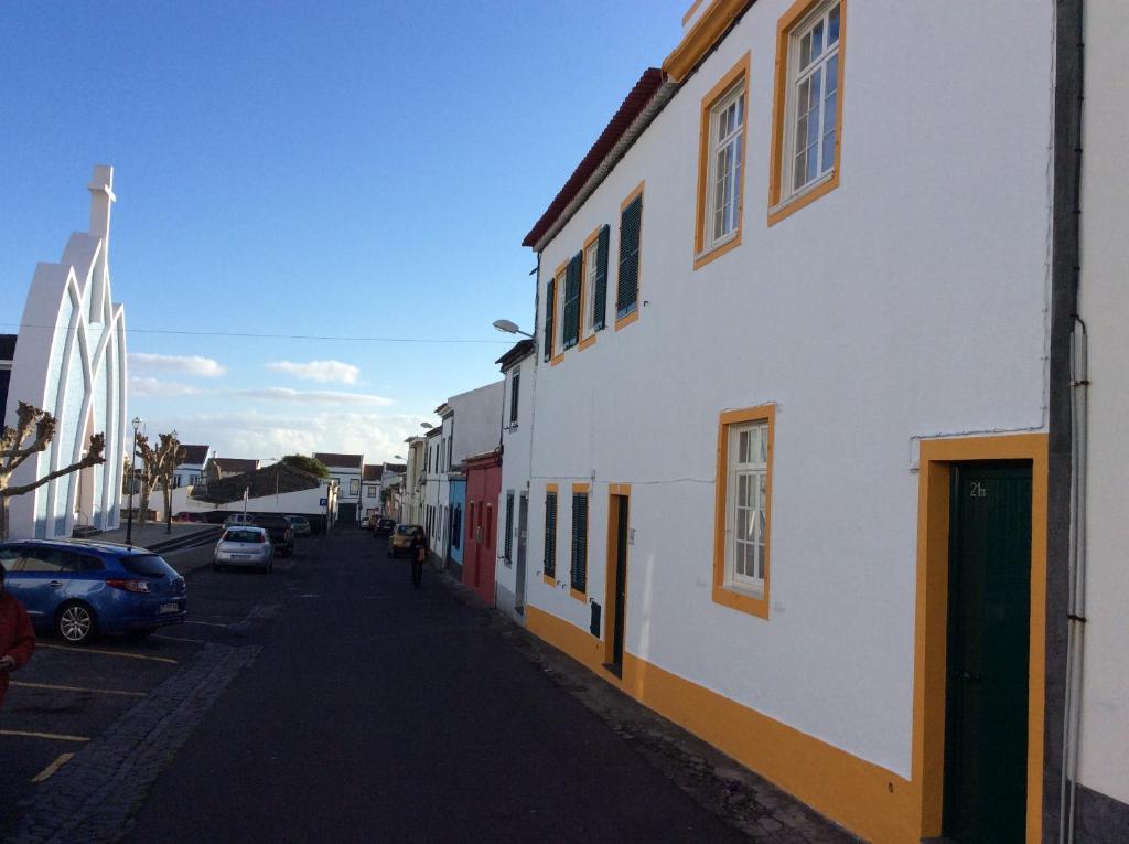 a street with a white building and cars parked on the street at Family House Garden in Ponta Delgada