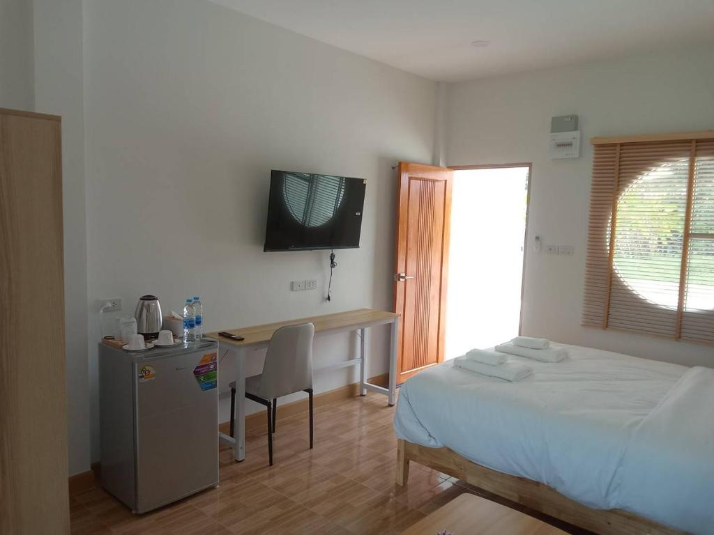 a bedroom with a bed and a desk and a television at MUJISTAY Hotel มูจิสเตย์โฮเทล in Ban Non Than
