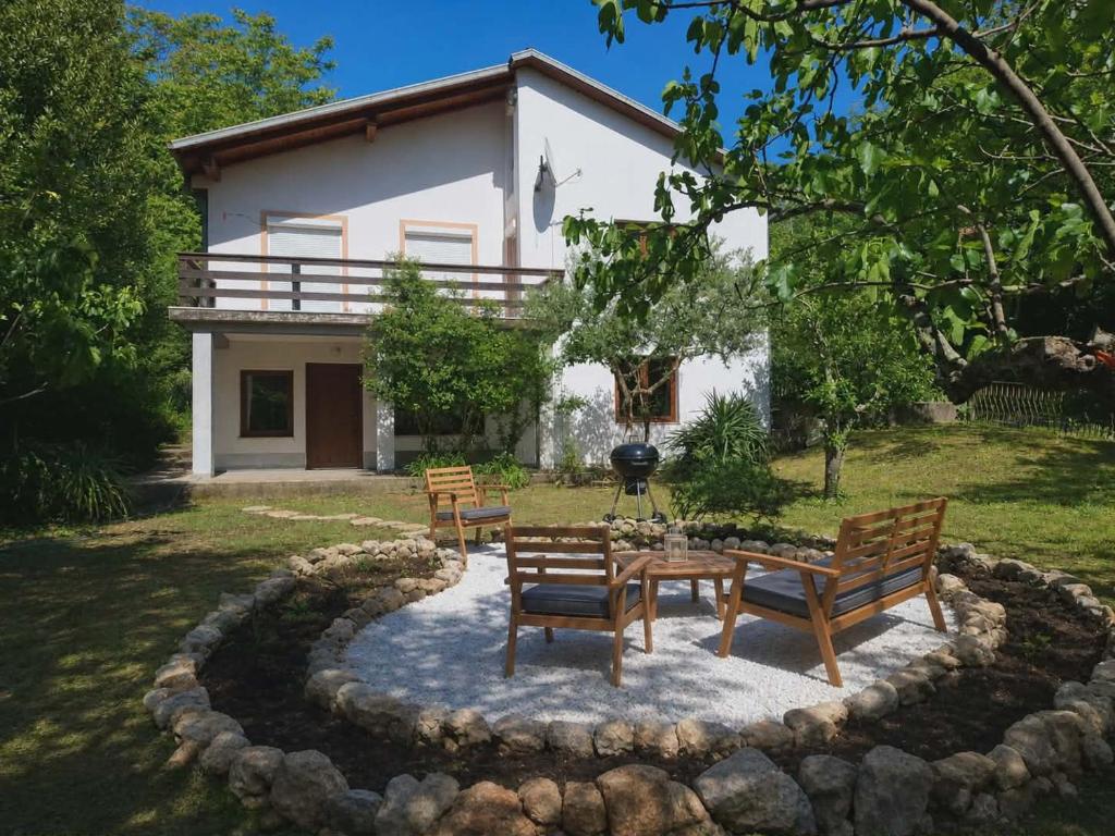 a group of benches sitting in a yard with a house at Jinn's Valley Apartment in Grižane