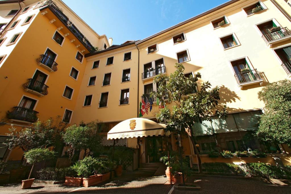 帕多瓦的住宿－Majestic Toscanelli (centro storico)，一座黄色的大建筑,前面有一棵树