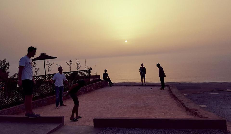a group of people standing near the water watching the sunset at Le Nid d'Aigle in Mirleft