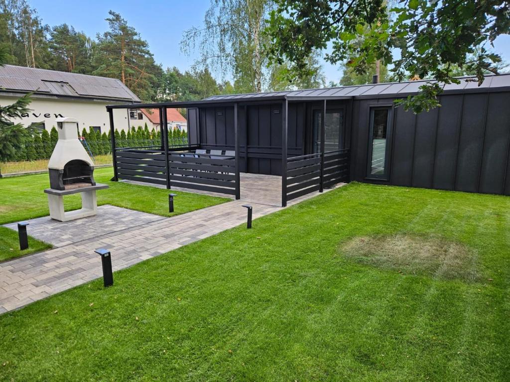 a backyard with a black house with a lawn at Domek Przy Jeziorze in Kujanki