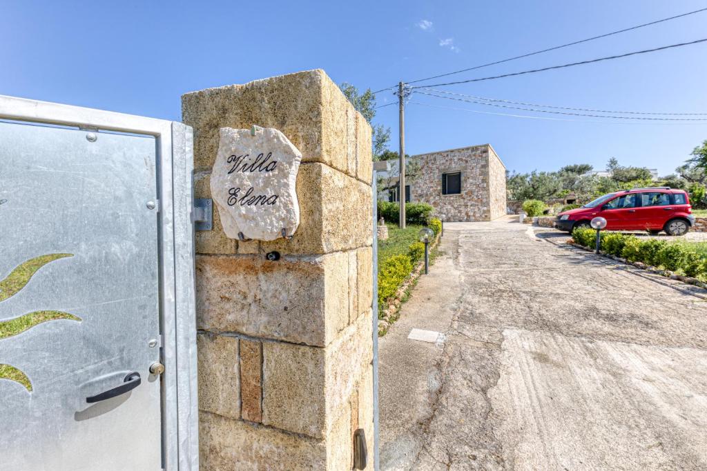 a stone wall with a sign on it next to a driveway at Villa Elena in Marina di Pescoluse
