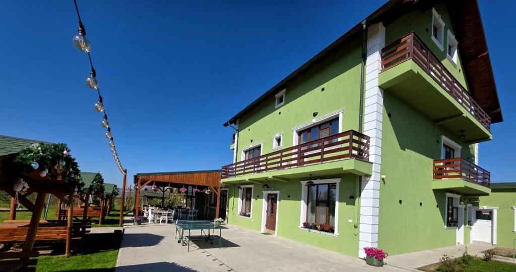 a green and white building with a patio at Colț de Rai in Hîrtoape