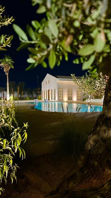 a large white building with a swimming pool at night at Athens Resort in Madīnat an Nahḑah