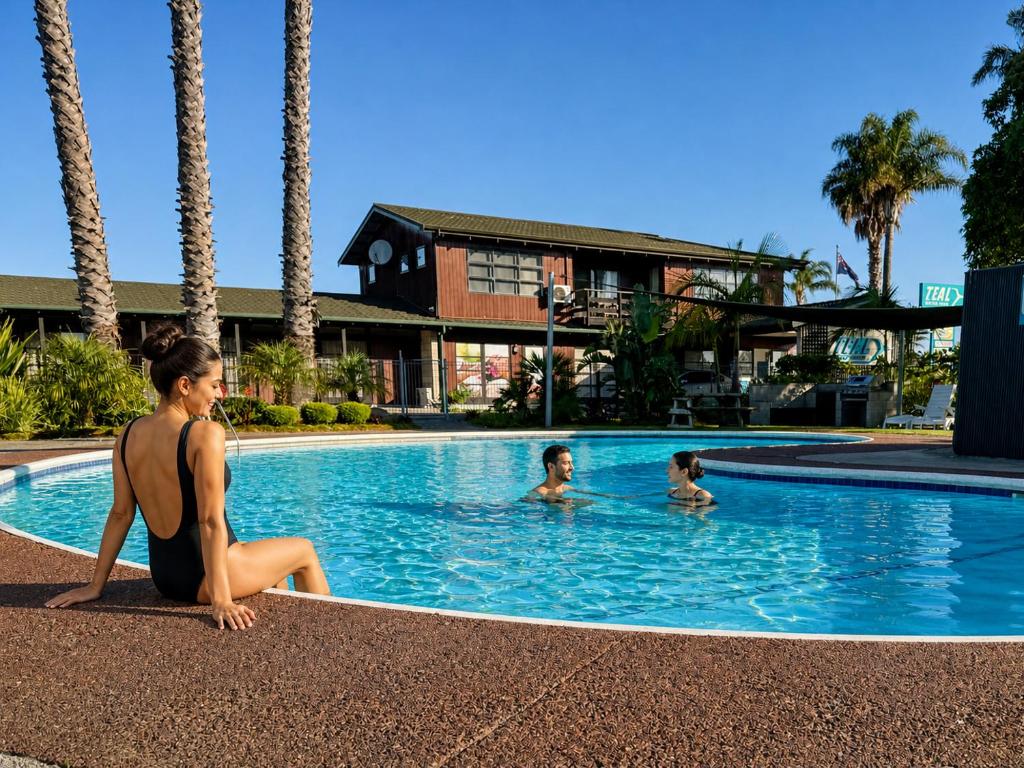 a woman in a bikini sitting in a swimming pool at Teal Motor Lodge in Gisborne