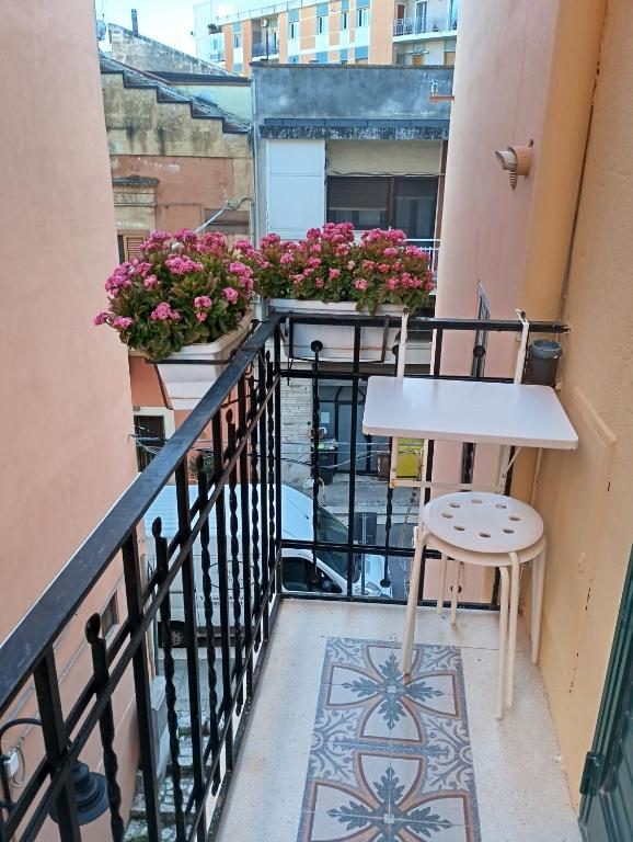 a balcony with a table and a stool and flowers at Dimora in pieno centro in Matera