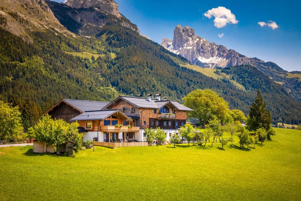 a house in a field with mountains in the background at Chalet Schintlbauer in Annaberg im Lammertal