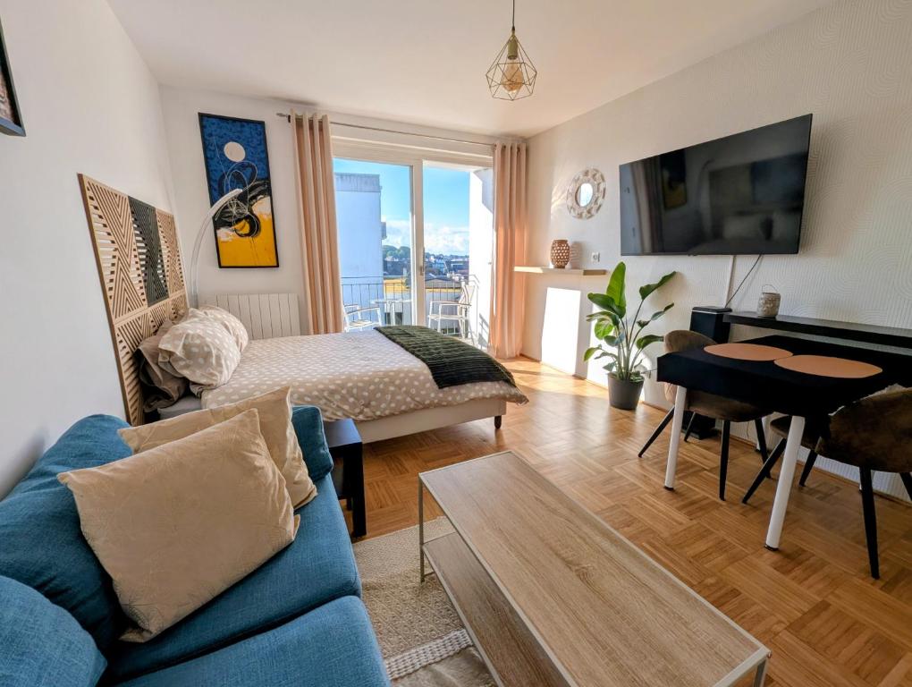 a living room with a bed and a blue couch at Appartement de charme in Concarneau