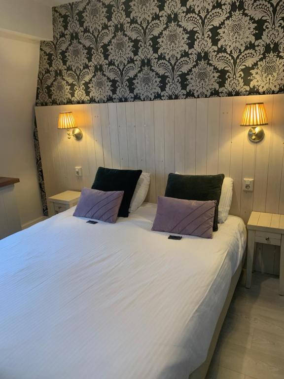 a bedroom with a large white bed with two tables at Logies La Dune Westende-Bad - Gratis parking in Middelkerke