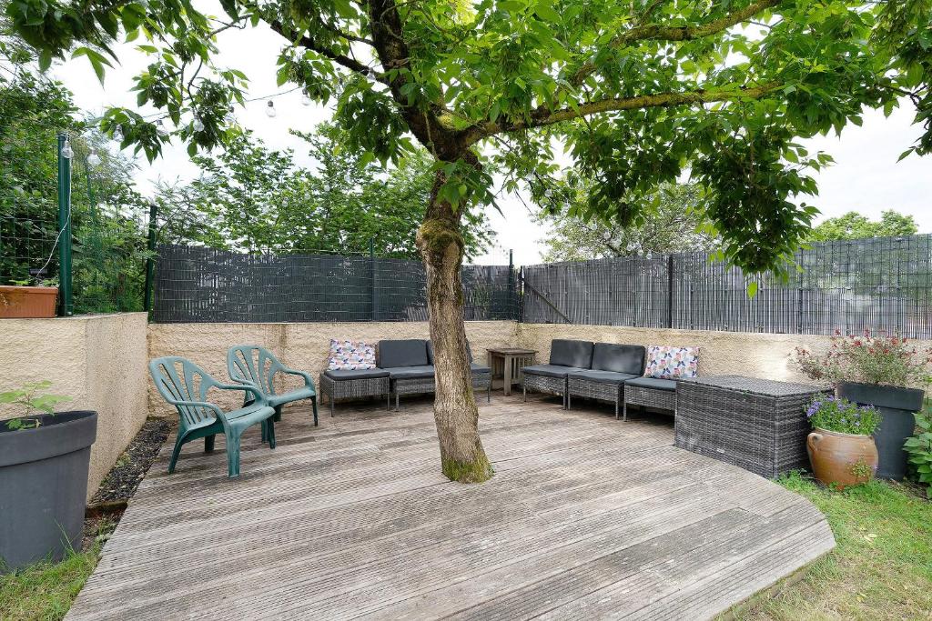 a patio with couches and a tree in a yard at Vacances chez Cali - Maison 10 pers in La Séguinière