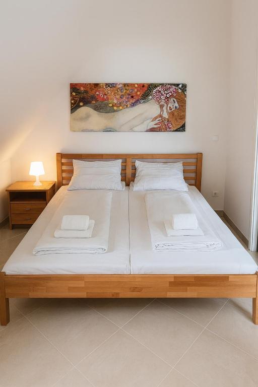 a bedroom with a large wooden bed with white sheets at Lakeview Apartment in Ostriach