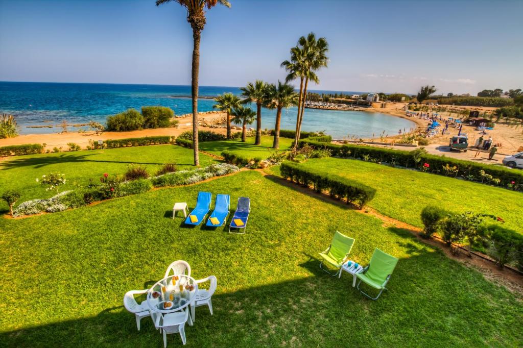 a lawn with a table and chairs and the ocean at Beachfront Trident in Protaras