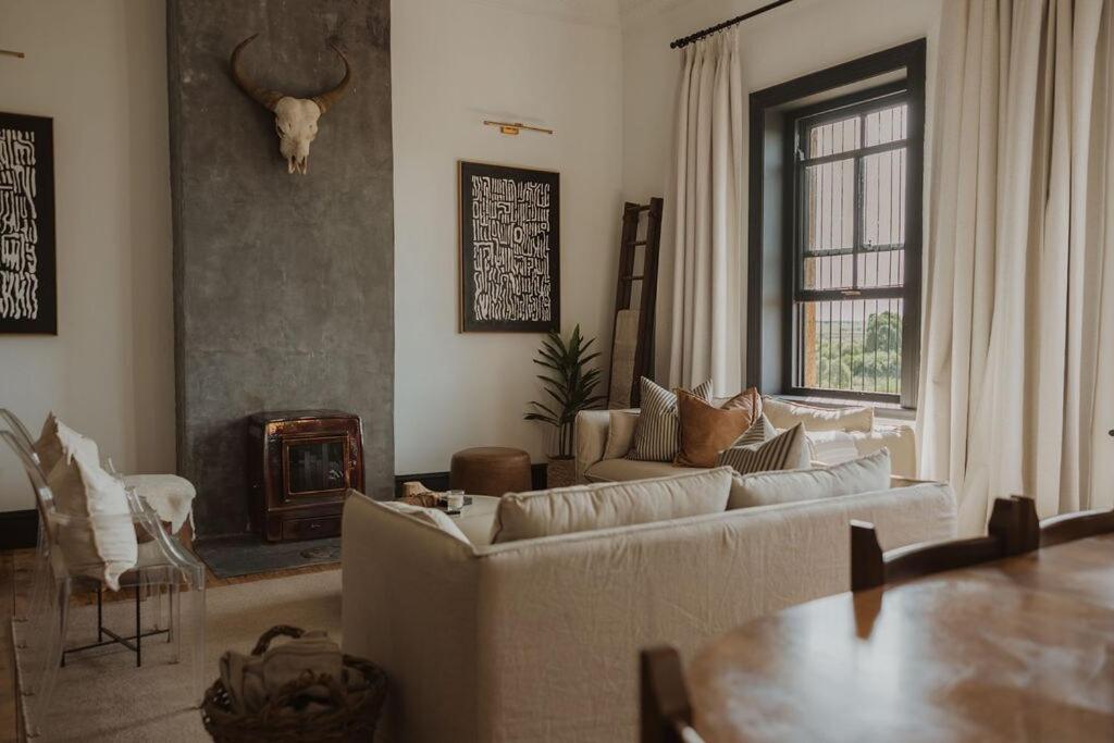 a living room with couches and a table and a fireplace at Waterval Guest Farm in Bloemfontein