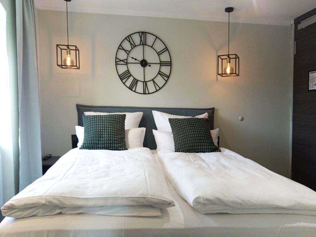 a bedroom with two beds with a clock on the wall at NOX HOTEL - Digital-Check-In - No Reception - nahe Bretten & Karlsruhe - 4 Essence in Wössingen