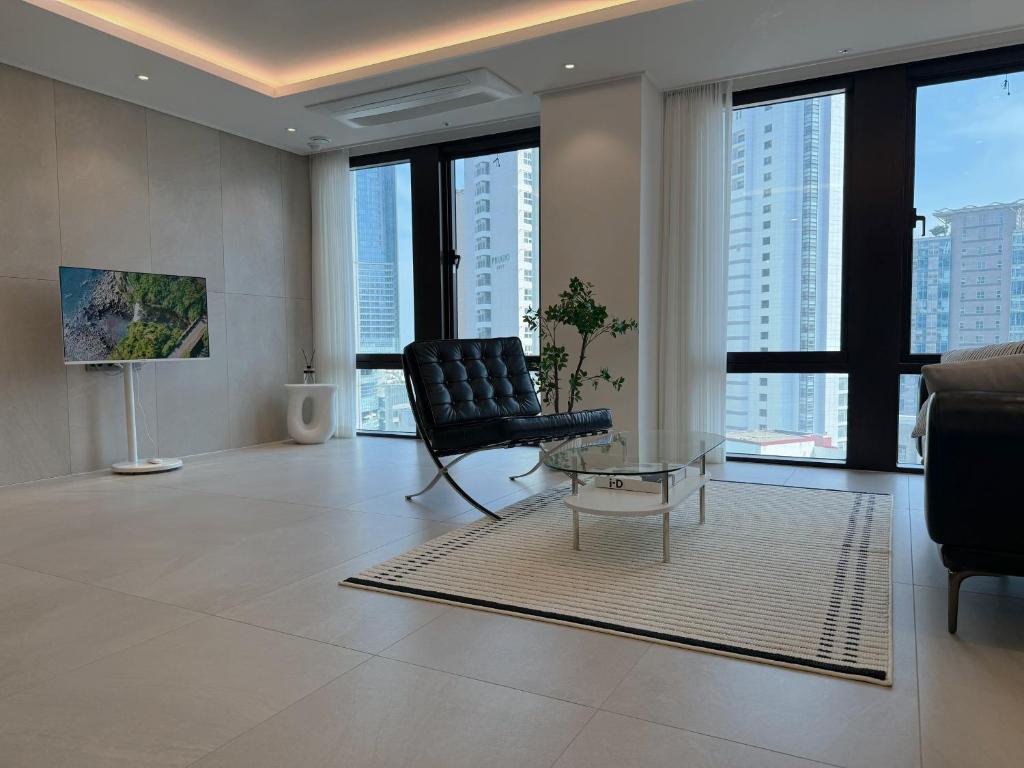 a living room with a chair and a glass table at Stay in MooD in Busan
