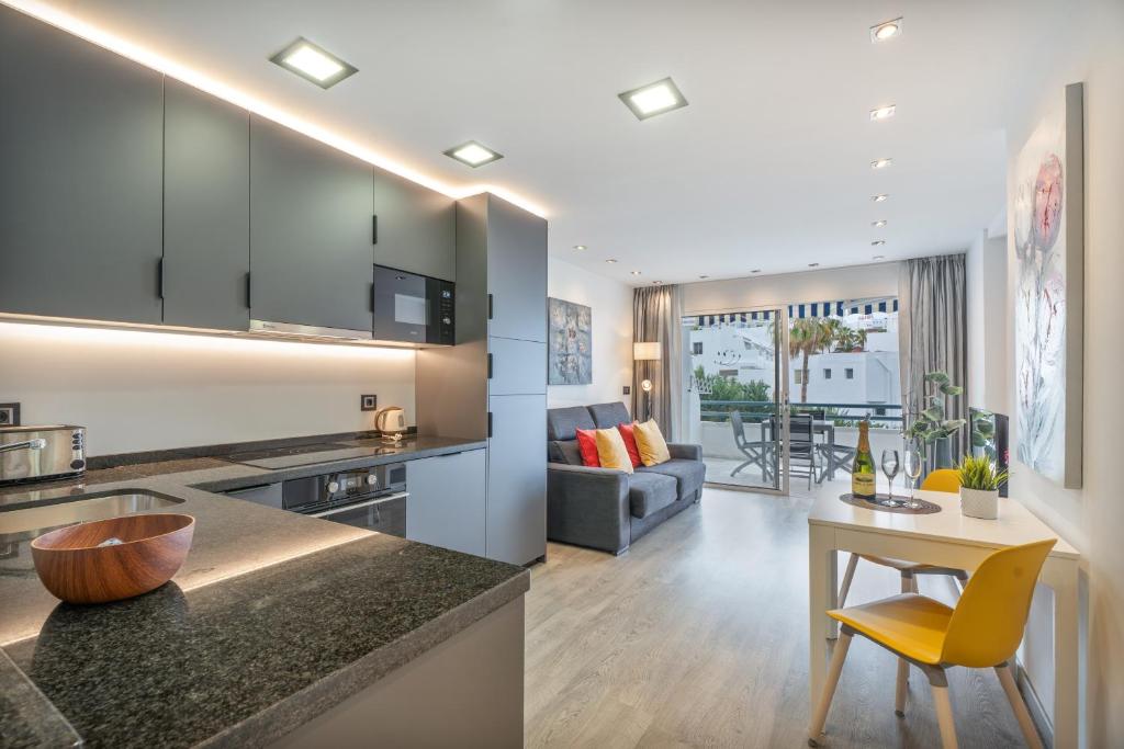 a kitchen and living room with a table and yellow chairs at Club Atlantis 159 in Adeje