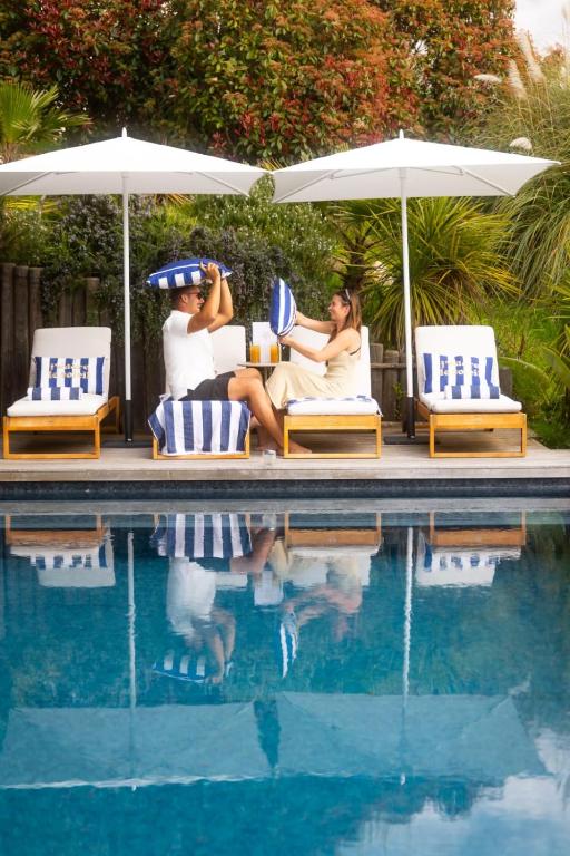 two people sitting on chairs next to a swimming pool at Villa Scappà Porticcio - Piscine & vue mer in Grosseto-Prugna