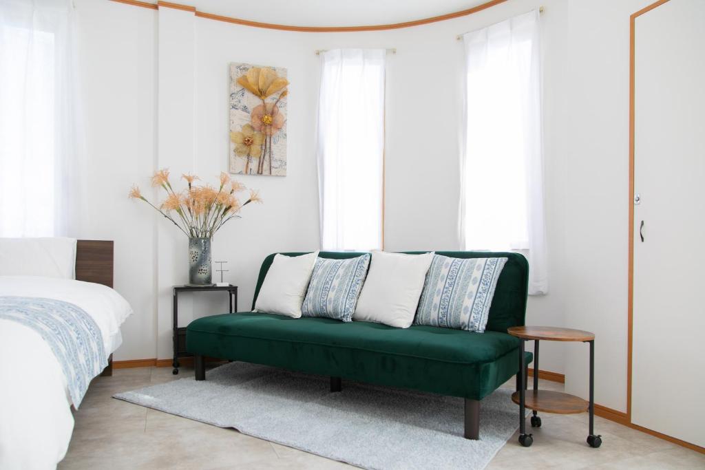 a green couch in a bedroom with a bed at ラベンダー富士 富士山と過ごすおしゃれな隠れ家 in Fuji