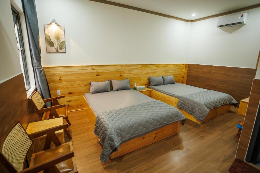 two beds in a room with wooden walls at Khách Sạn Vân Nguyên in Buôn Ea Yông